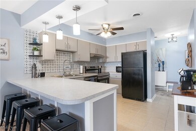 Kitchen featuring a peninsula, black appliances, open shelves, light countertops, and decorative backsplash