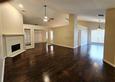 Unfurnished living room featuring vaulted ceiling, ceiling fan, a fireplace with flush hearth, dark wood finished floors, and recessed lighting