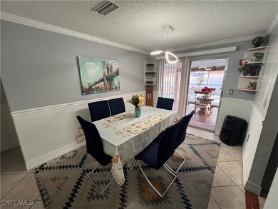 Dining area featuring light tile patterned floors, a textured ceiling, and crown molding