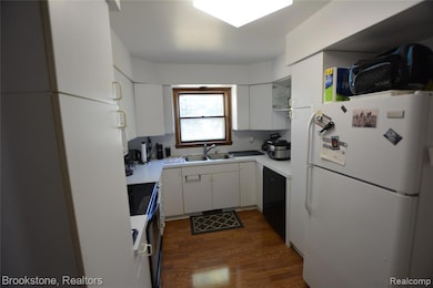 Kitchen featuring freestanding refrigerator, white cabinets, light countertops, dark wood finished floors, and open shelves