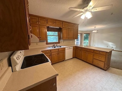 Kitchen featuring white appliances, a sink, ceiling fan, a peninsula, and light countertops