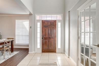 Foyer with light tile patterned floors, healthy amount of natural light, and ornamental molding