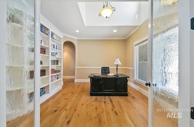 Office area with arched walkways, ornamental molding, light wood finished floors, recessed lighting, and built in features