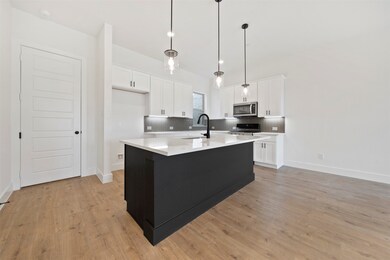 Kitchen featuring backsplash, white cabinetry, and an island with sink