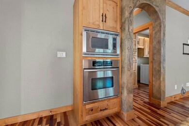 Kitchen with stainless steel appliances, arched walkways, light wood finished floors, and light brown cabinets