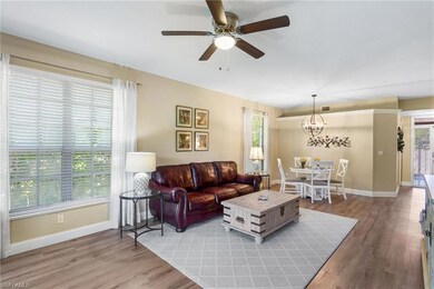 Living room with light wood finished floors, ceiling fan, and a chandelier