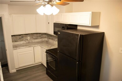 Kitchen featuring decorative backsplash, white cabinetry, refrigerator, dark hardwood / wood-style floors, and black electric range