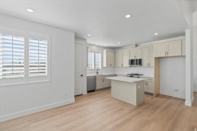 Kitchen with a kitchen island, recessed lighting, stainless steel appliances, light wood-style floors, and a textured ceiling