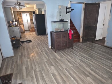 Kitchen with arched walkways, freestanding refrigerator, dark wood-style floors, and a ceiling fan