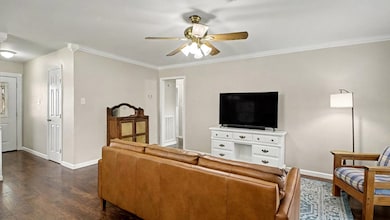 Bright and welcoming living room with crown molding, updated flooring, and plenty of wall space for your entertainment setup. The open layout makes it easy to style and enjoy.