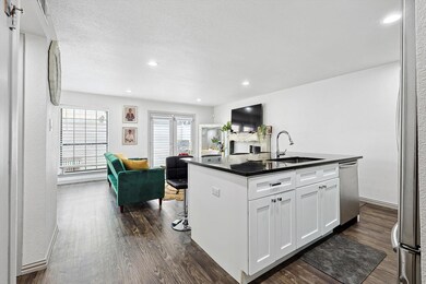 Kitchen with dishwasher, dark wood-type flooring, sink, a kitchen island with sink, and white cabinetry