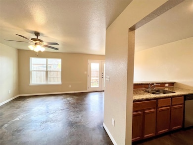 Kitchen with stainless steel dishwasher, concrete flooring, a ceiling fan, a textured ceiling, and light countertops