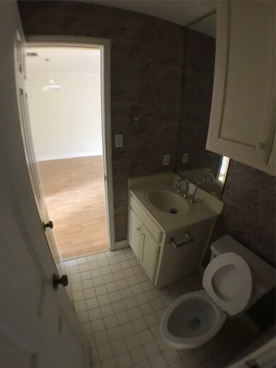 Half bath with wallpapered walls, vanity, tile pa
