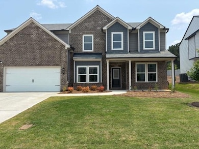 View of front of home with brick siding, concrete driveway, a front yard, and central air condition unit