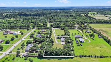 Aerial view of property and surrounding area featuring property parcel outlined and a forest