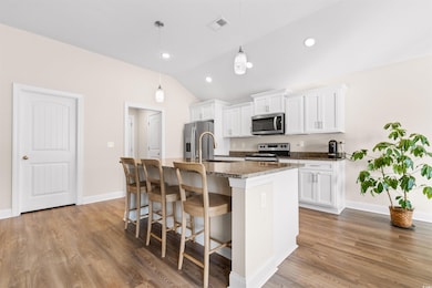 Kitchen with visible vents, an island with sink, a