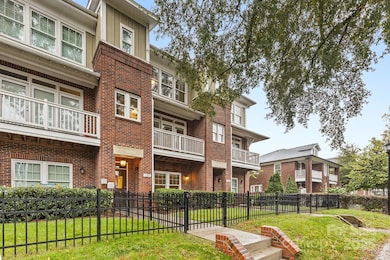 Elegant multi-level brick exterior highlighted by detailed trim, covered balconies, and a private fenced entry. Lush greenery complements the timeless curb appeal