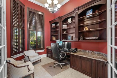 Office area with built in study area, a chandelier, ornamental molding, and light tile patterned floors
