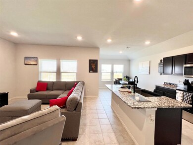 Kitchen with light stone counters, light tile patterned floors, a center island with sink, recessed lighting, and stainless steel appliances