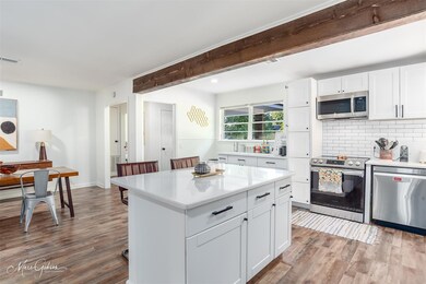 Kitchen featuring white cabinetry, backsplash, woo