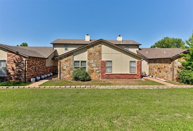 Rear view of house with a chimney, stone siding, a yard, and a shingled roof