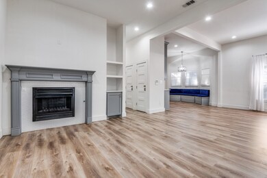 Unfurnished living room with light wood finished floors, a glass covered fireplace, beamed ceiling, and recessed lighting