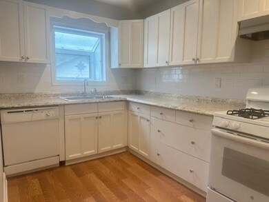 Kitchen with white cabinets, a sink, white applian