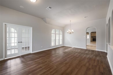 Empty room featuring arched walkways, dark wood f
