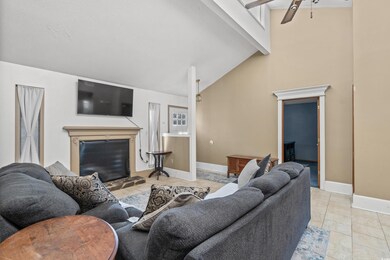 Tiled living room featuring vaulted ceiling with b