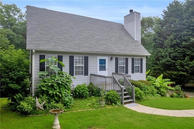 Cape cod house with a chimney, a front lawn, and roof with shingles