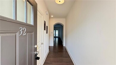 Hall with arched walkways, dark wood-style flooring, baseboards, and recessed lighting