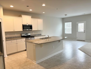 Kitchen featuring dark stone counters, a sink, sta