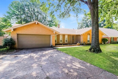 Ranch-style house with brick siding, driveway, a front yard, and an attached garage