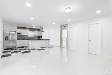 Kitchen with white cabinetry, wall chimney exhaust hood, decorative backsplash, light tile patterned floors, and appliances with stainless steel finishes
