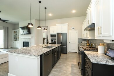 Imagine a dream kitchen where the functional island shines with ample storage, a sleek black stainless-steel dishwasher, and a recessed sink featuring a brushed gold arched pull-down faucet. Positioned conveniently next to your 5-burner gas range with a stylish hooded vent, this setup offers abundant counter workspace in a space that blends practicality with elegance.