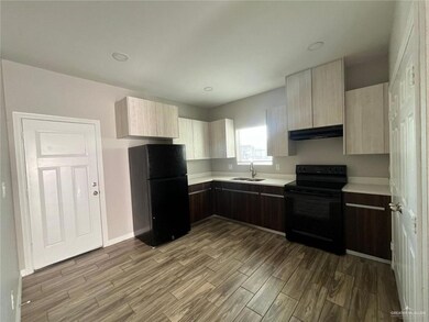 Kitchen featuring black appliances, light countertops, exhaust hood, and wood finished floors