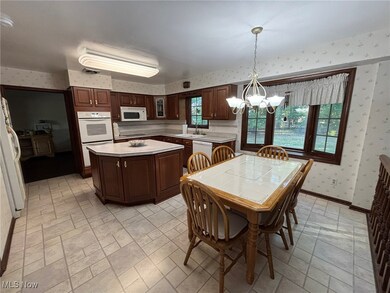 Kitchen featuring wallpapered walls, light countertops, white appliances, a chandelier, and pendant lighting