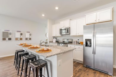 Kitchen with an island with sink, a sink, white ca