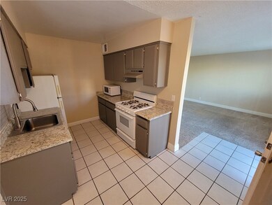 Kitchen featuring gray cabinetry, light tile patterned floors, white appliances, under cabinet range hood, and a textured ceiling