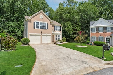 View of front facade featuring driveway, a garage, a front yard, and stucco siding