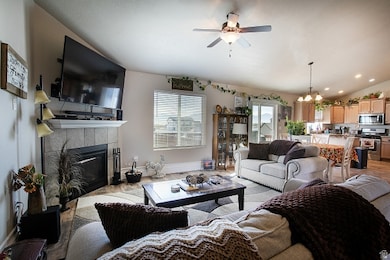 Living area featuring a fireplace, lofted ceiling, a ceiling fan, a chandelier, and recessed lighting