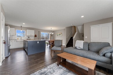 Living area featuring baseboards, an inviting chandelier, dark wood finished floors, stairway, and recessed lighting