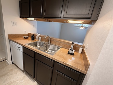 Kitchen featuring light countertops, white dishwasher, dark brown cabinets, and ceiling fan