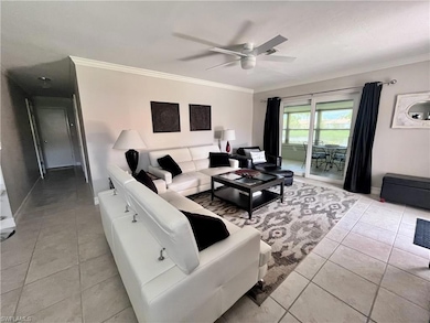 Living area featuring ceiling fan, light tile floors, and ornamental molding