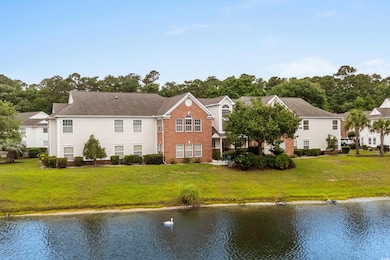 Back of house with a water view, a lawn, and brick siding