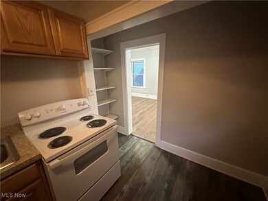 Kitchen with white electric range, dark wood-type flooring, and brown cabinets