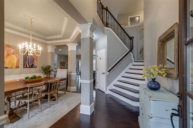 The open floor plan features soaring ceilings for an airy foyer. The large dining room is just to the left and steps into the kitchen.