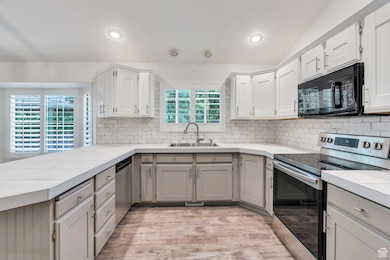 Kitchen featuring appliances with stainless steel finishes, tile counters, gray cabinetry, backsplash, and light wood-type flooring