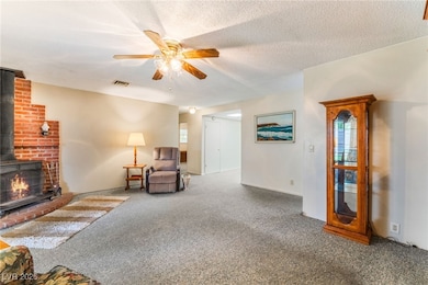 Carpeted living area with a wood stove, ceiling fa