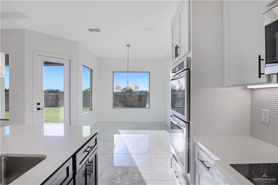 Kitchen with black electric cooktop, visible vents, stainless steel double oven, pendant lighting, and light countertops